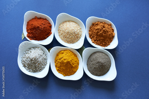 Spices close-up in bowls on a blue background. 