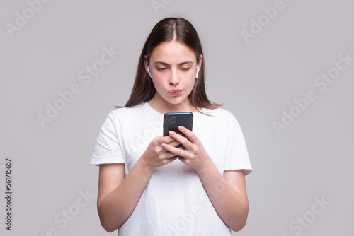 Funny woman uses mobile phone happy texting in social networks. Young beautiful woman with smart phone.