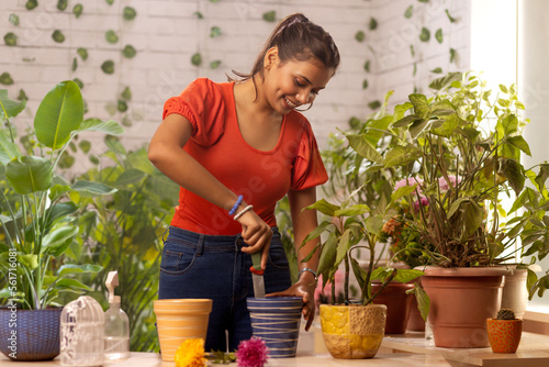 Young woman preparing soil for planting while gardening at home