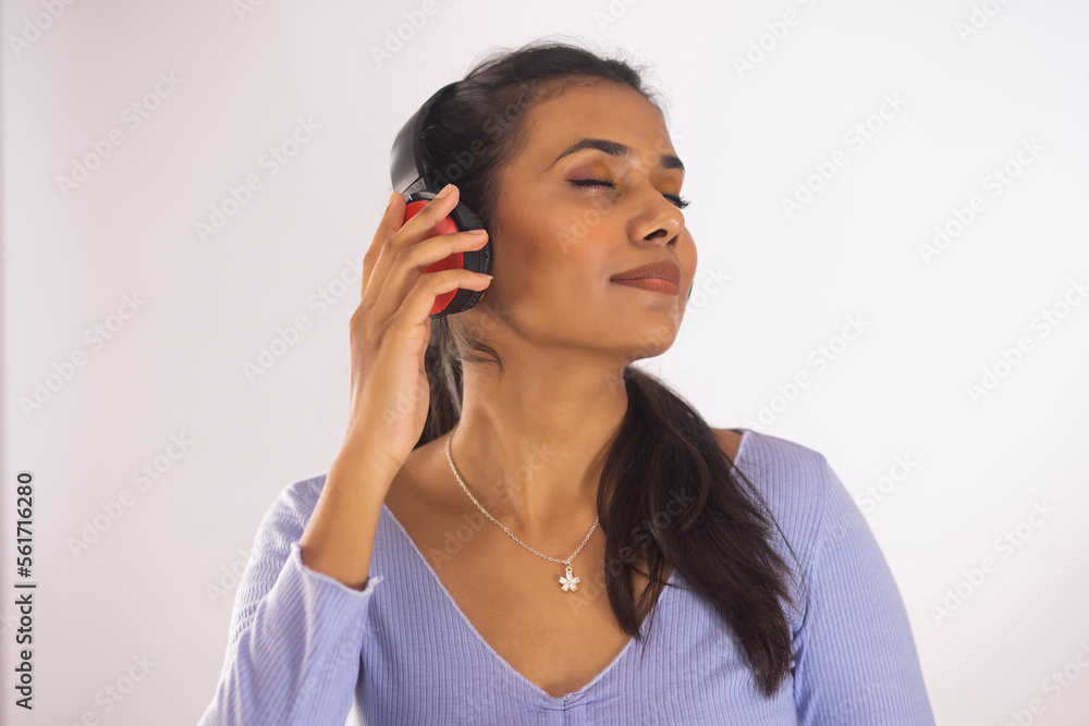 Close-up portrait of woman with eyes closed listening music on headphone Close-up portrait of woman with eyes closed listening music on headphone