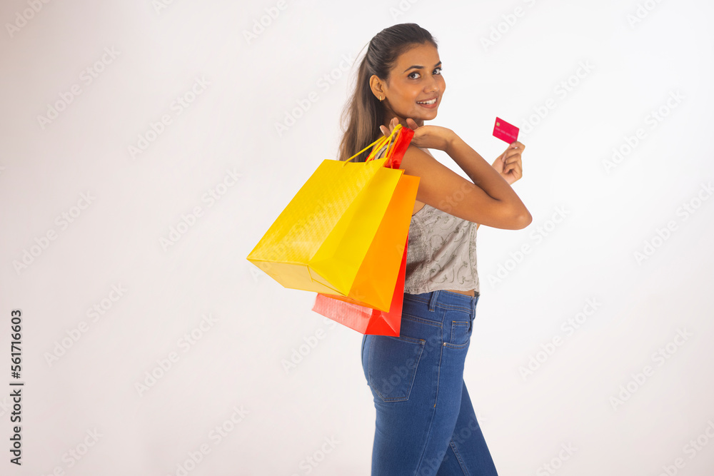 Portrait of happy woman holding shopping bags and credit card against white background
