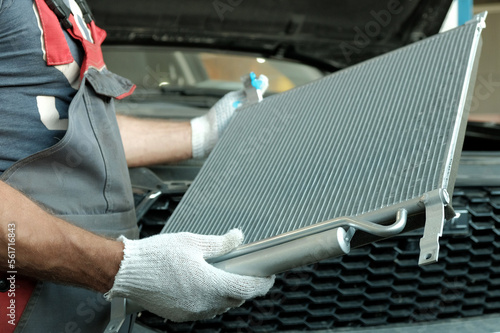 Spare parts for the car. Engine cooling radiator. An auto mechanic inspects a new radiator before installation. Car repair in a car service center.
