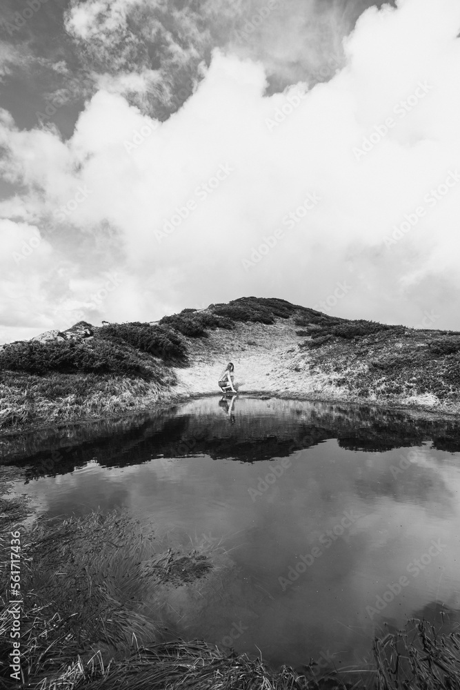 Female tourist on lake bank monochrome landscape photo. Beautiful nature scenery photography with sky on background. Idyllic scene. High quality picture for wallpaper, travel blog, magazine, article