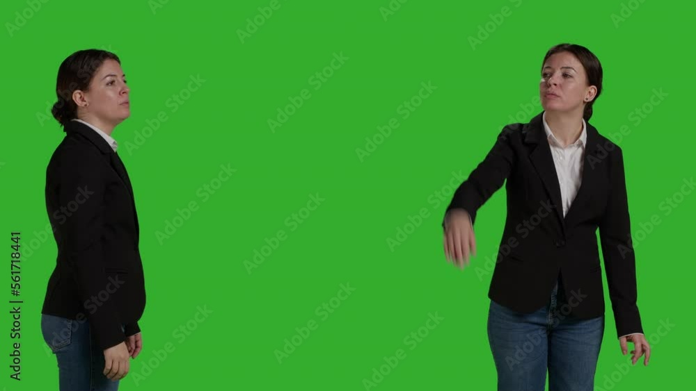Close up of office manager raising arm and waving to call someone over, standing over isolated greenscreen backdrop. Young employee asking and calling people over to talk, businesswoman. Close up of office manager raising arm and waving to call someone over, standing over isolated greenscreen backdrop. Young employee asking and calling people over to talk, businesswoman.