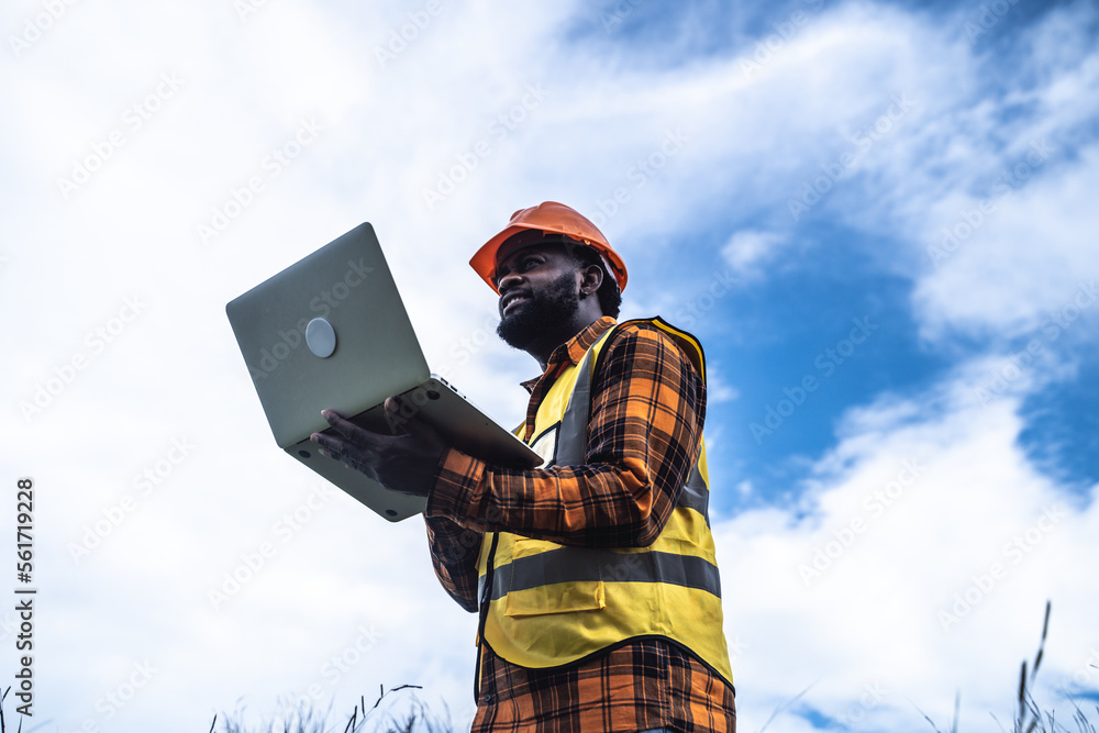 Portrait of engineer African American man working with laptop in wind turbine farm. Portrait of engineer African American man working with laptop in wind turbine farm.