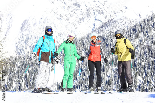 group of four friends at a ski resort posing on a slope in winter