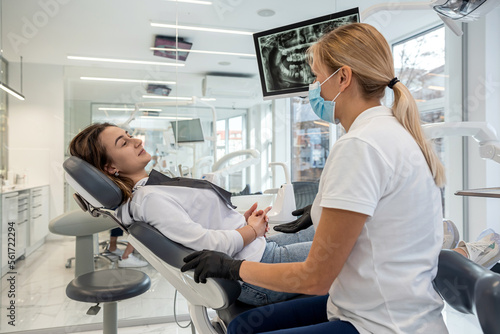 Dentist and patient choose treatment during consultation with medical equipment in dentistry.