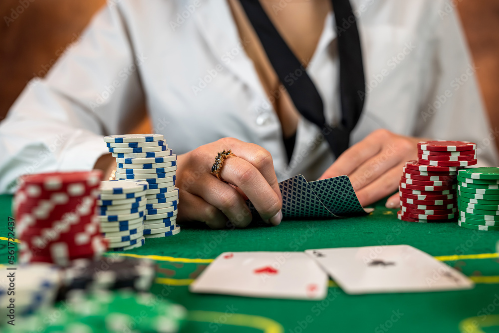 woman's hand takes poker chips from a pile at a round poker table. woman's hand takes poker chips from a pile at a round poker table.