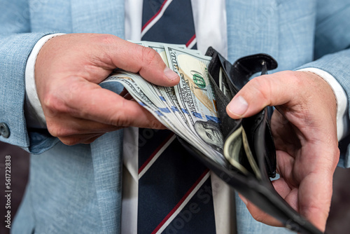 closeup businessman hand holding money dollar in black wallet purse