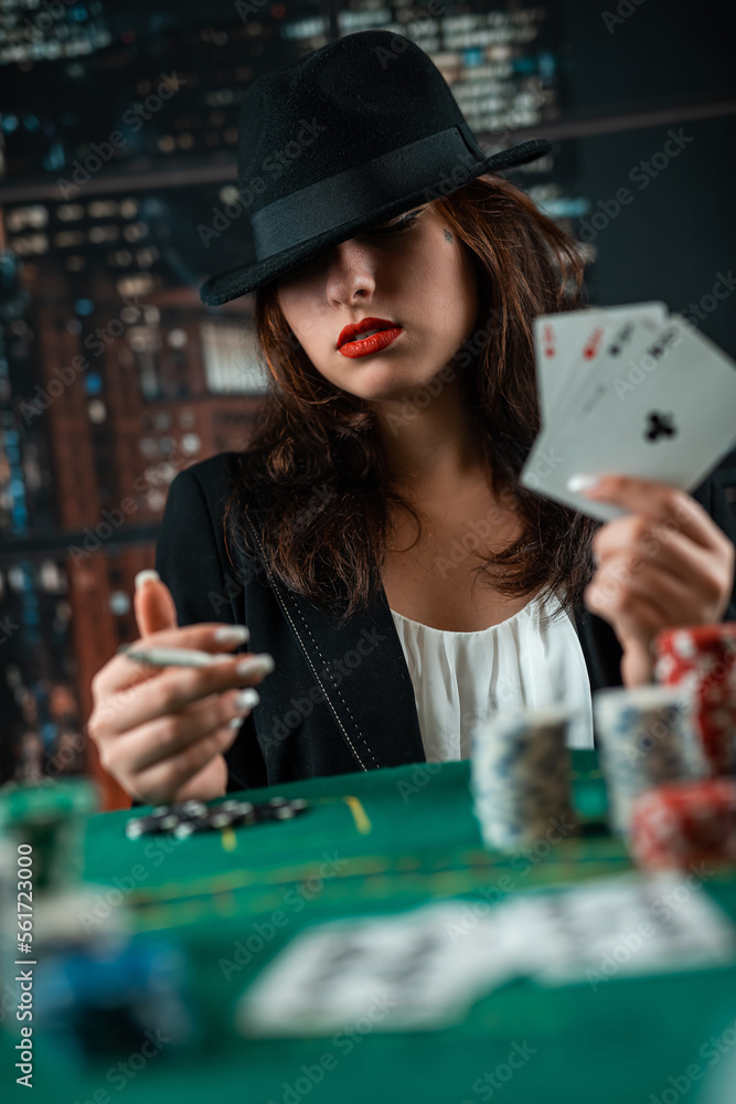Female hand with playing cards and poker chips and burning cigar close-up in front of poker table. poker concept Female hand with playing cards and poker chips and burning cigar close-up in front of poker table. poker concept