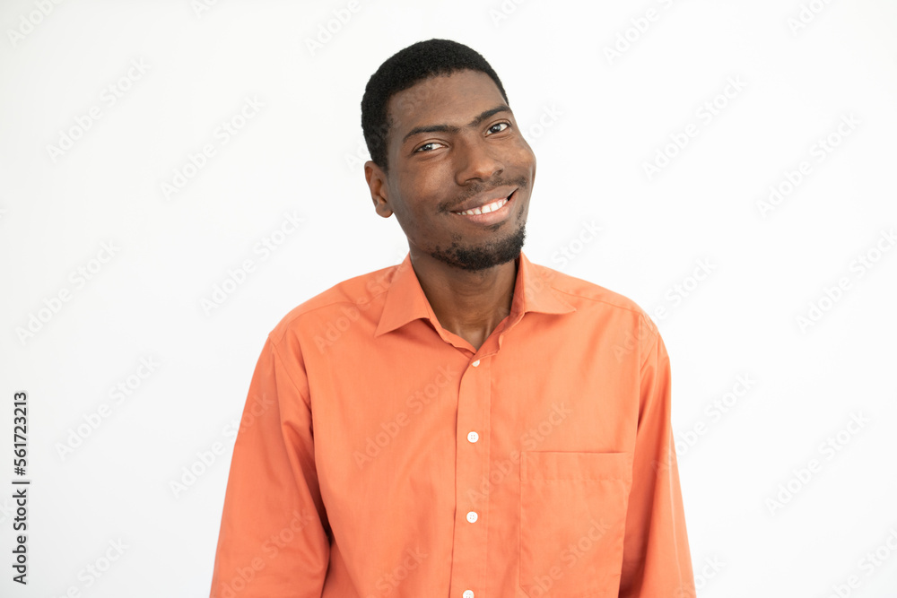 Fototapeta premium Portrait of positive young man looking at camera and smiling. African American guy wearing orange shirt posing over white background. Positivity concept