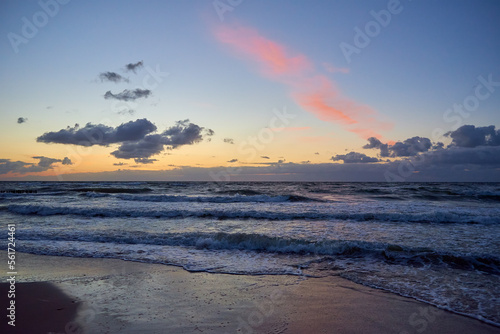 Sea coastline with waves. Baltic sea against dramatic cloudy sky at sunset. Panoramic nature landscape