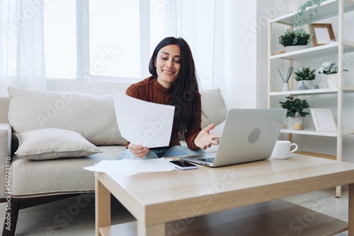 Smile woman working from home on laptop, freelance work online with documents