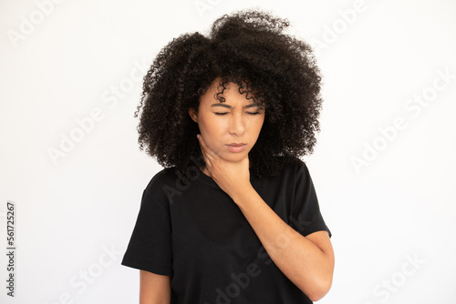Portrait of of ill young woman touching throat over white background. Biracial lady with afro hairstyle wearing black T-shirt suffering from sore throat. Diseases concept © KAMPUS