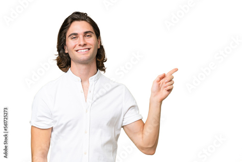 Young caucasian man isolated on green chroma background pointing finger to the side