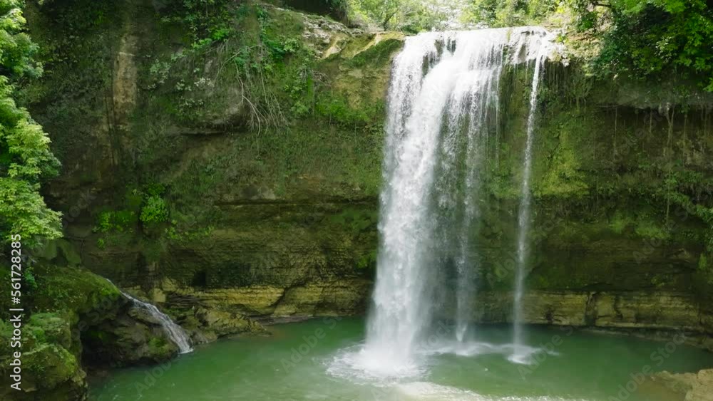 Waterfall in the tropical forest in slow motion. Aerial view of Ben-Ben Falls waterfall in a mountain gorge. Negros, Philippines. Waterfall in the tropical forest in slow motion. Aerial view of Ben-Ben Falls waterfall in a mountain gorge. Negros, Philippines.