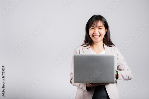 Woman smiling confident smiling holding using laptop computer and typing keyboard for online sending email or chat, Portrait excited happy Asian young female studio shot isolated on white background