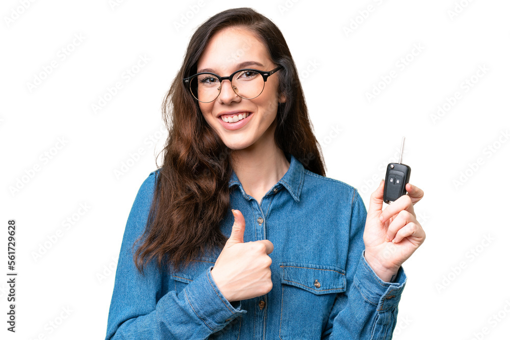 Young caucasian woman holding car keys over isolated background with thumbs up because something good has happened Young caucasian woman holding car keys over isolated background with thumbs up because something good has happened