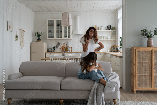 Angry parent, mother yelling at teen girl daughter while arguing at home. Problems between parents and teenagers. Mom shouting at stubborn, difficult child. Harsh parenting, parental anger concept photo