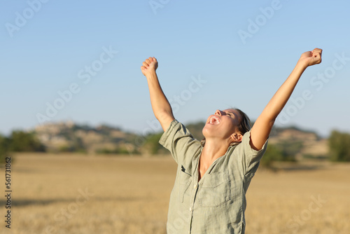 Excited woman raising arms in a field