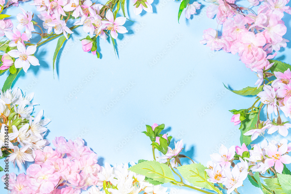 Beautiful spring nature background with blossom flowers, petal on light blue background , top view, frame. Springtime holiday flat lay copy space