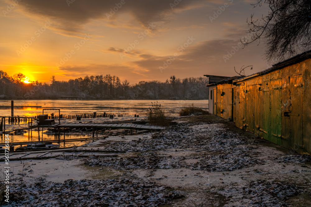 Fishing boat garages in a marina on a frozen river during a beautiful sunrise