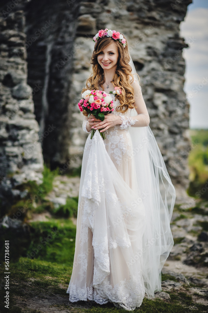 Young beautiful girl in elegant dress is standing and holding hand bouquet of pastel pink flowers and greens at nature. The bride holds a wedding bouquet outdoors. Young beautiful girl in elegant dress is standing and holding hand bouquet of pastel pink flowers and greens at nature. The bride holds a wedding bouquet outdoors.