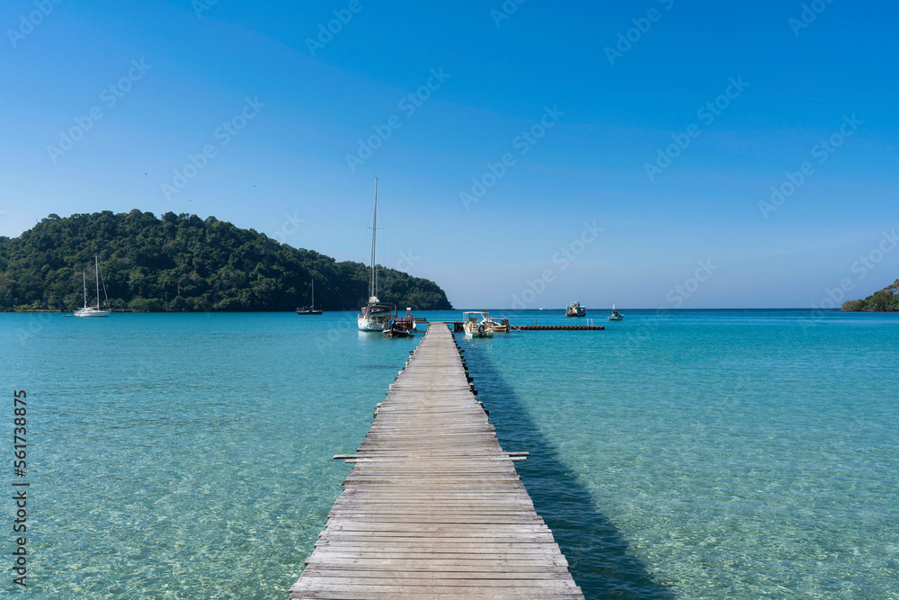 Obraz premium Scenery of wooden pier in the tropical sea and sightseeing boat anchored in sunny day on summer at Koh Kood