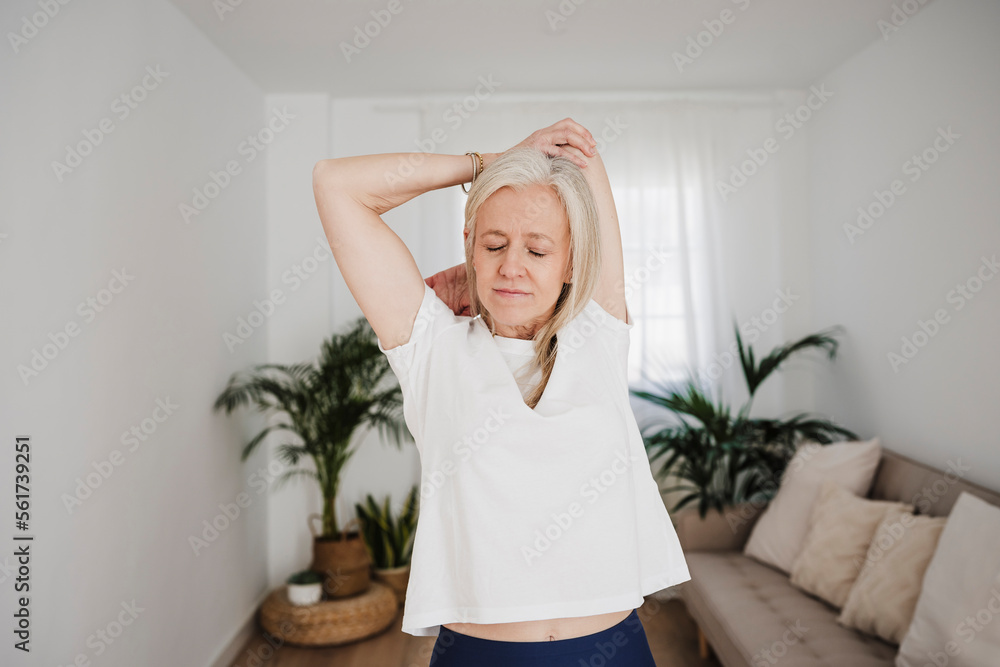Mature woman stretching arms and exercising at home Mature woman stretching arms and exercising at home