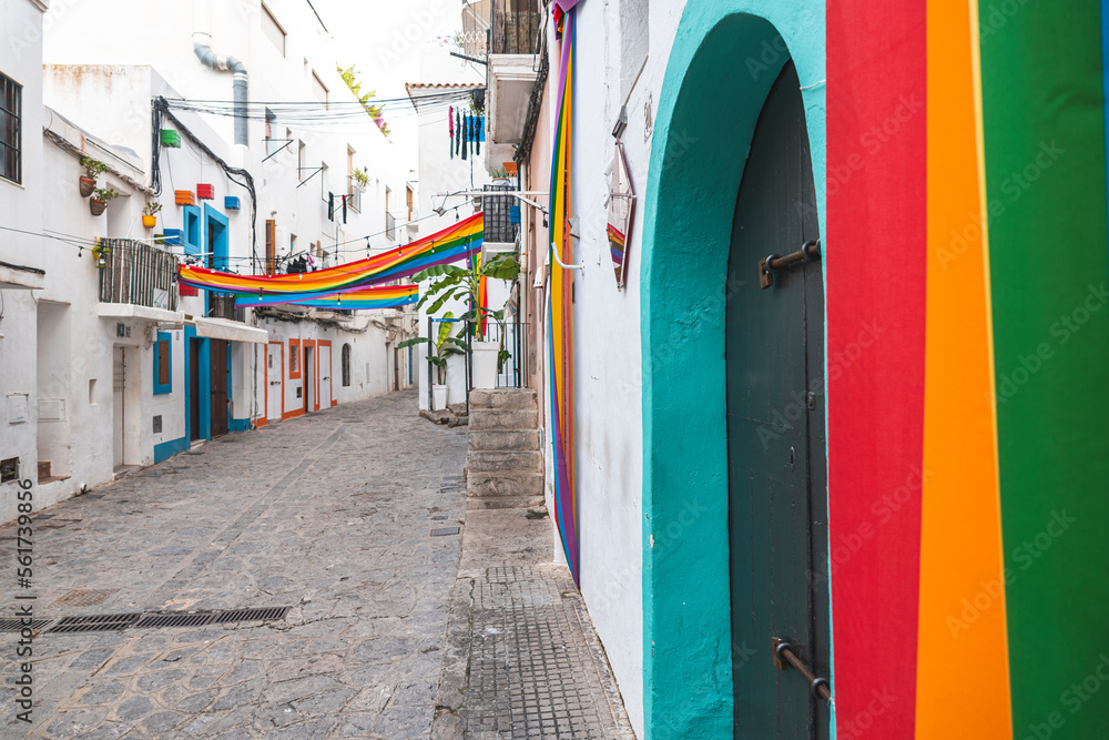 Spain, Balearic Islands, Ibiza, Rainbow flags hanging over town alley