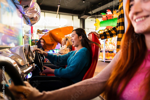 Young women having fun with driving simulator in arcade photo