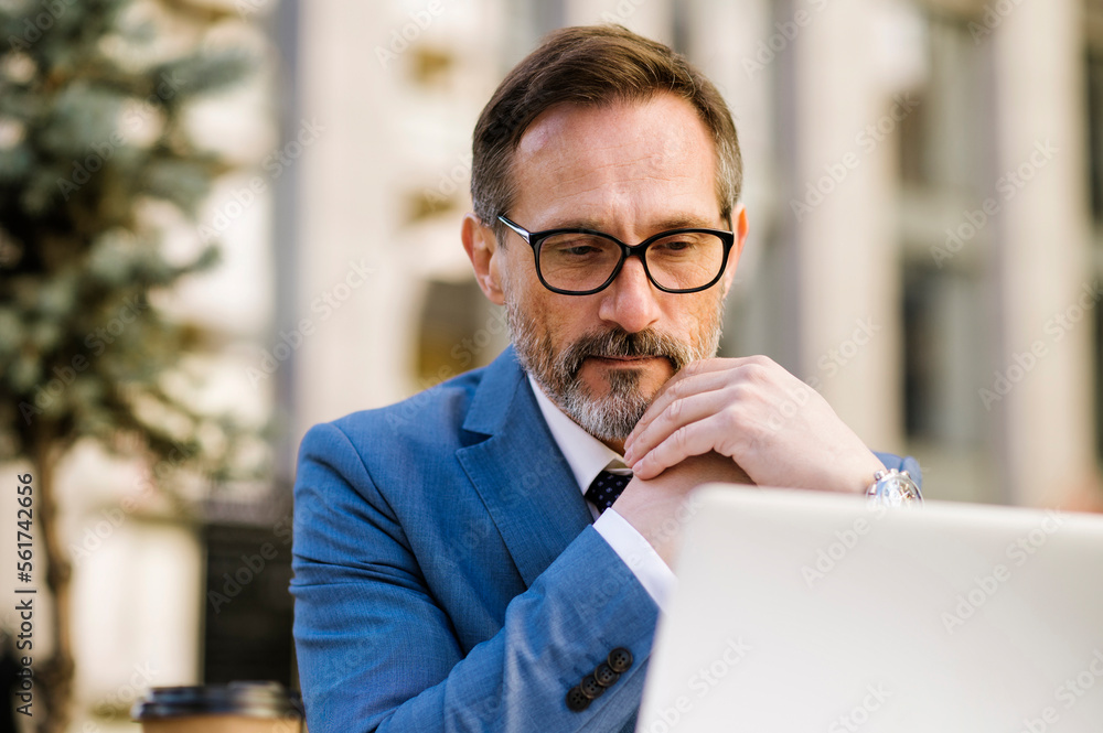 Mature businessman watching laptop sitting at cafe Mature businessman watching laptop sitting at cafe