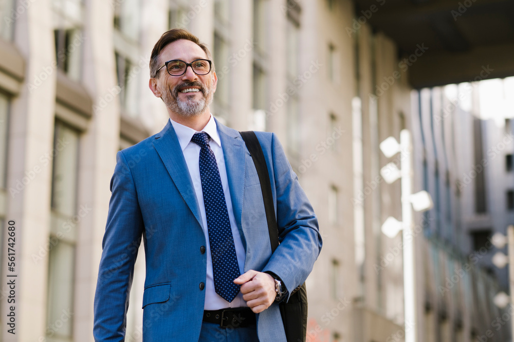 Happy mature businessman walking outside building Happy mature businessman walking outside building