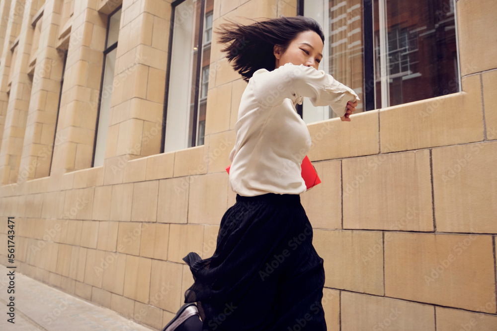 © Westend61 - Businesswoman checking time and running by building on footpath