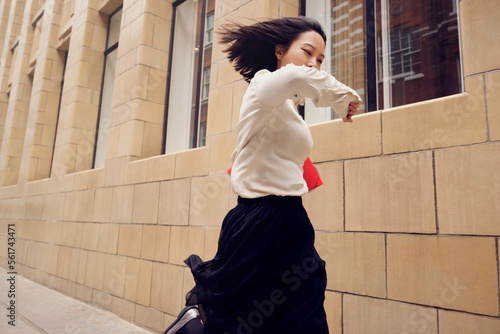 Businesswoman checking time and running by building on footpath