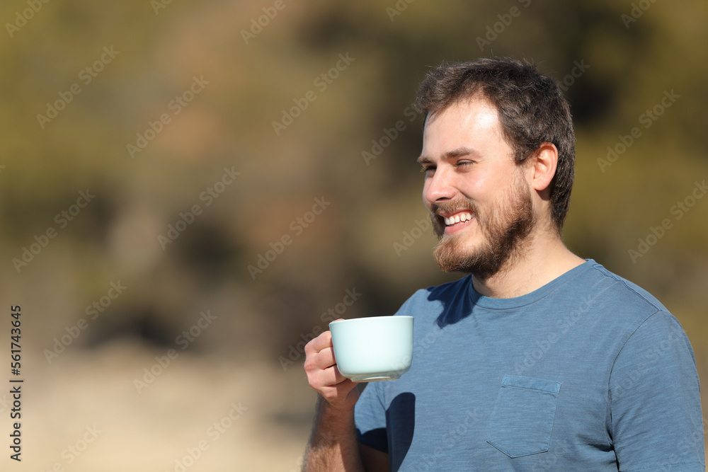 Happy man holding coffee cup contemplating views in nature Happy man holding coffee cup contemplating views in nature