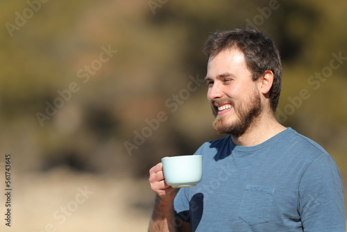 Happy man holding coffee cup contemplating views in nature