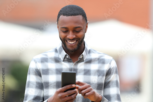 Happy black man walking using smart phone