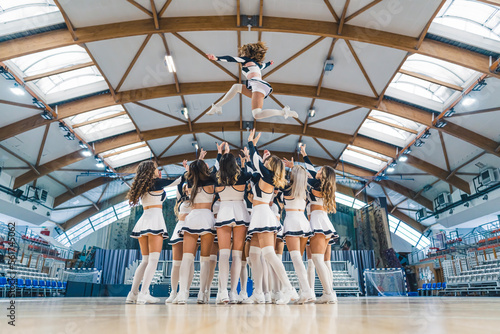 Full shot of a cheerleading squad hrowin one of their teammates high up in the air. Sport concept. High quality photo photo