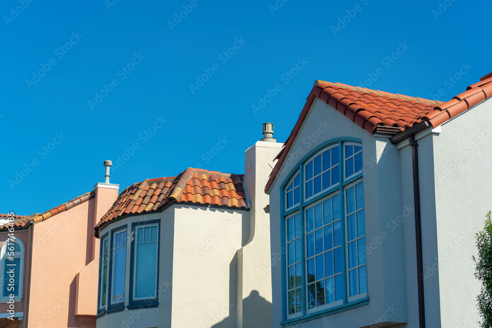 Decorative house facades with orange adobe stone roofs and stucco exteriors with orange white and blue homes