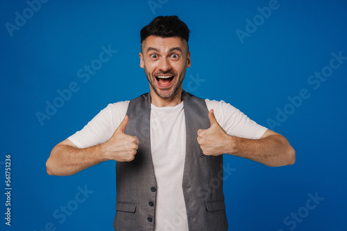 Excited positive man showing two thumbs up isolated over blue wall
