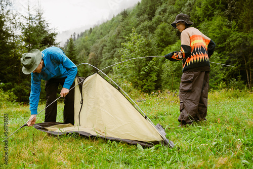 Young white people putting up tent while hiking in mountain forest