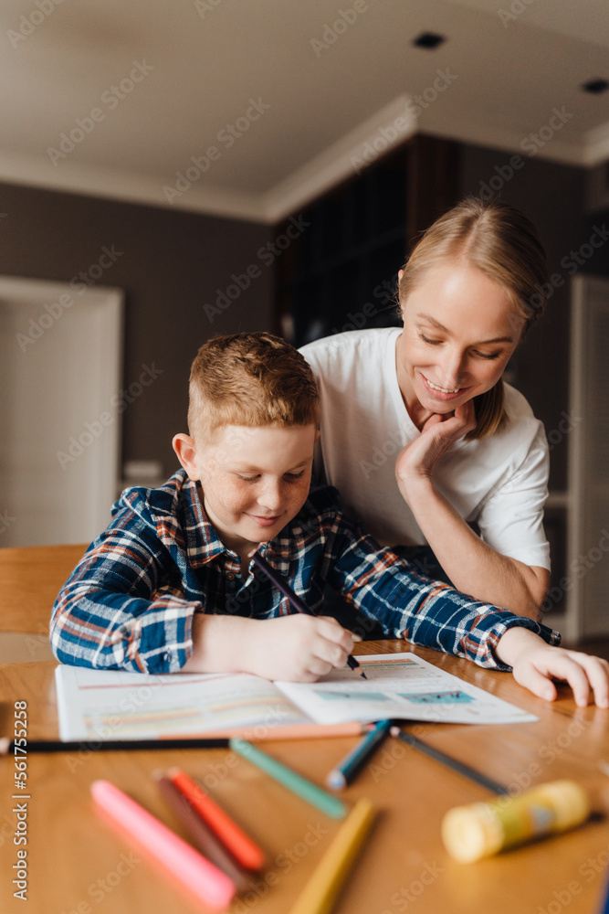 Smiling mother and her son doing homework together Smiling mother and her son doing homework together