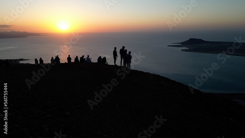 Spain, Lanzarote, Canary island - drone view of people silhouette on amazing sunset in Mirador del Rio on the Risco de Famara - Tourist looking the sun and the ocean sea - Travel in Lanzarote 