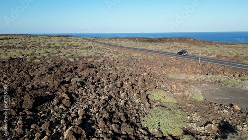 Spain , Canaries - car passing through street road immersed in the nature in volcanic landscape with the volcano - trip to the island of Lanzarote biosphere reserve in the Timanfaya national park 