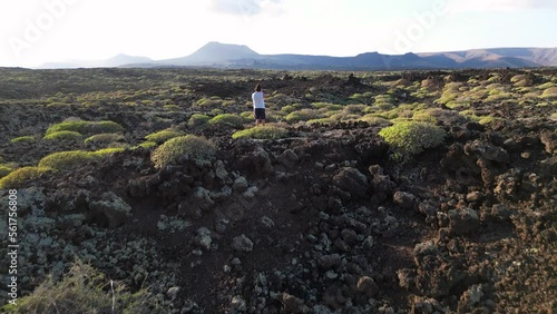 Drone aerial view of man photographer taking pictures immersed in amazing volcanic landscape in Biosfere reserve of Lanzarote Canaries Spain - travel and shooting with camera the power of nature  photo