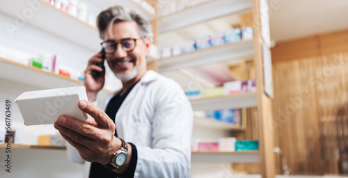 Obraz na plátně Drug store pharmacist holding a medication box and talking to a patient on the p