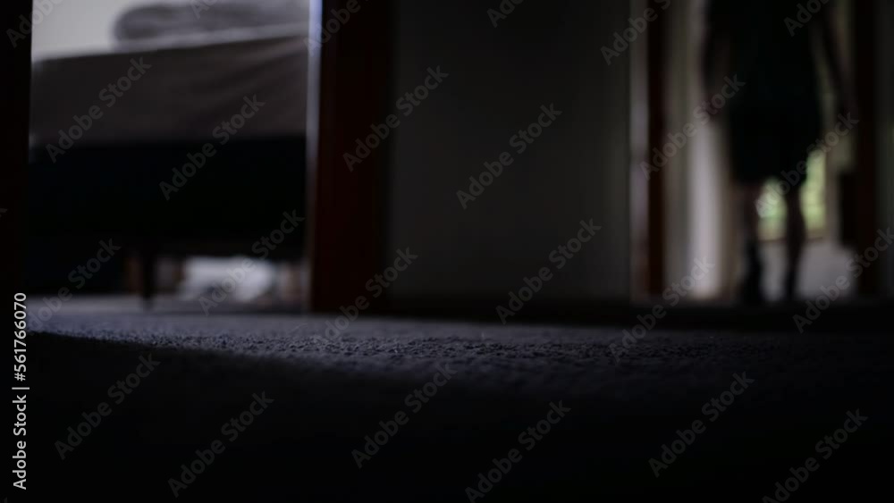 Person in shorts coming into frame and walking down a dark hallway at home Person in shorts coming into frame and walking down a dark hallway at home