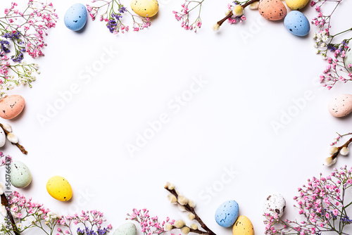 Beautiful Easter composition with spring flowers and colorful quail eggs over white background. Springtime and Easter holiday concept with copy space. Top view