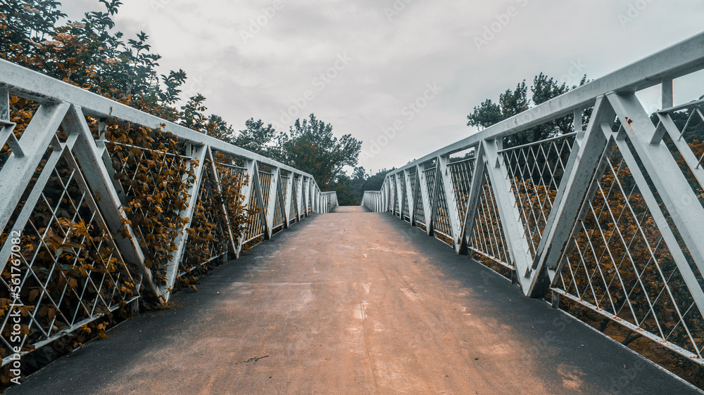 Fototapeta premium walkway with a bridge of asphalt and a white fence over the river in a park of Gijon, Asturias